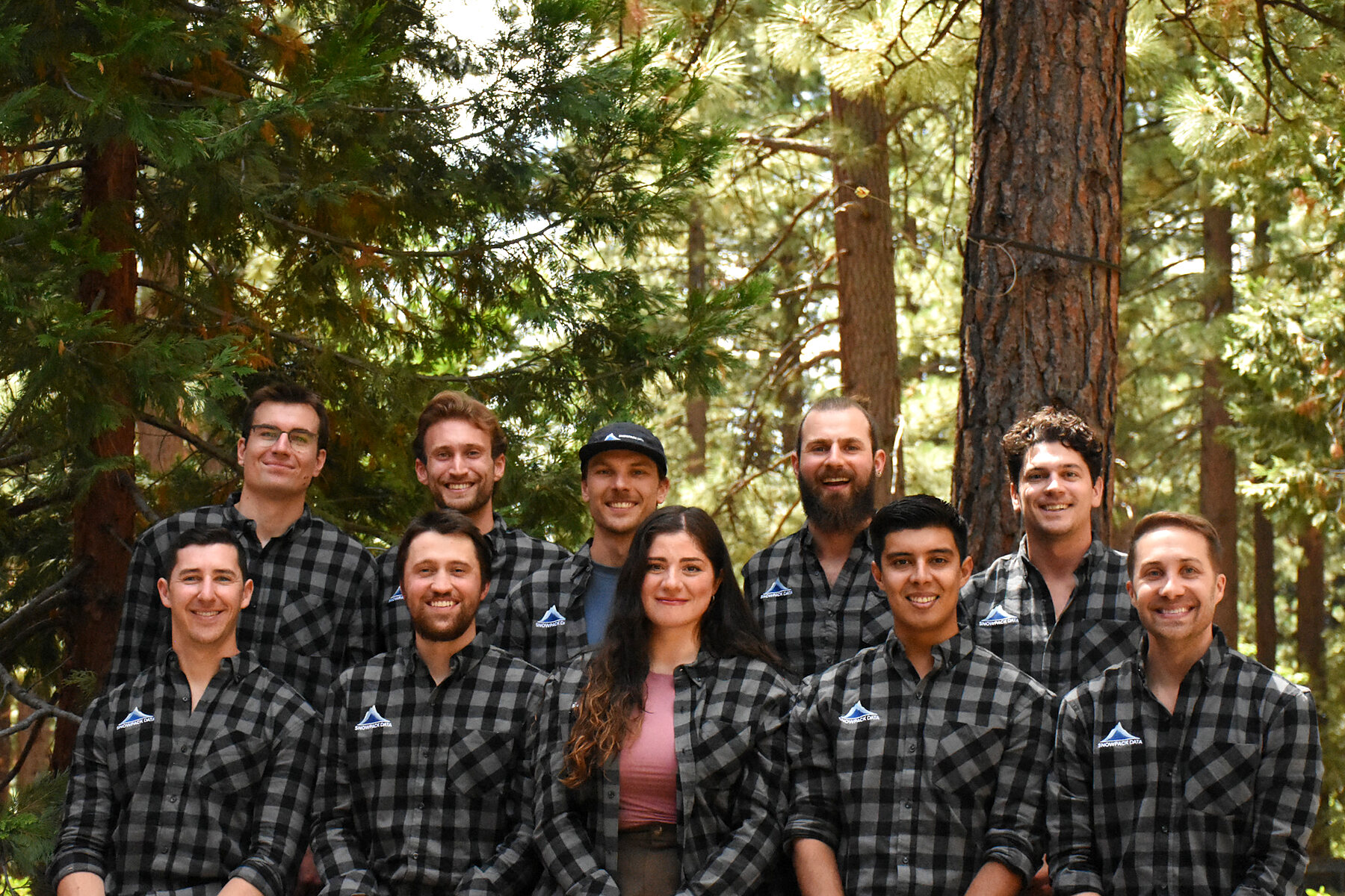 The Snowpack Data team standing together among the trees at the 2026 team retreat